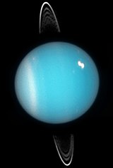 横倒しになった天王星。南半球には線状の雲、北半球には明るい雲も見える。
